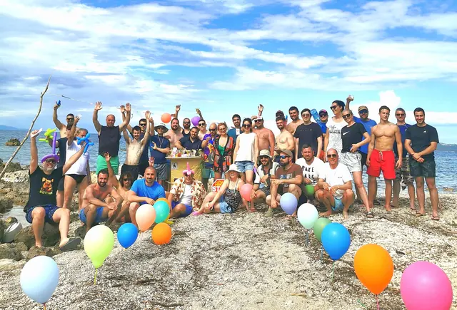The team on a rocky beach with balloons, arms in the air
