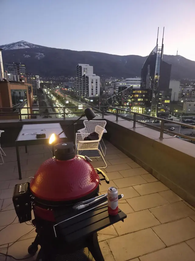 The office terrace at dusk, with a kamado grill and Vitosha mountain behind the city